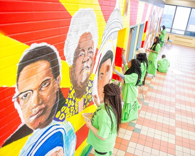 Photo of students painting a wall at a school