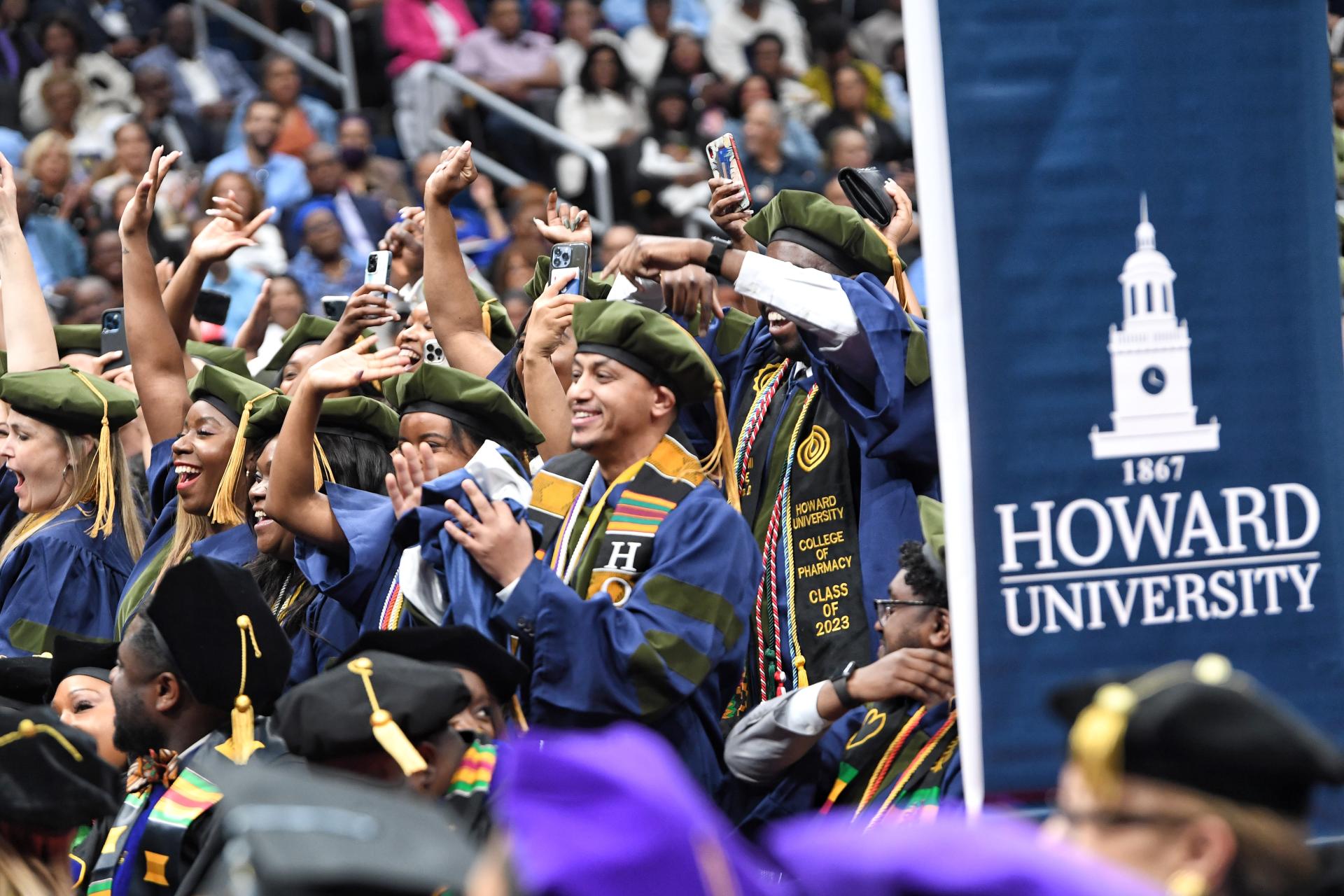 graduates next to a Howard University sign