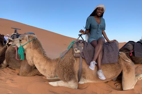 student sitting on camel in desert