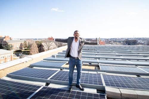 Gilbert Campbell standing on roof at Howard University among solar panels
