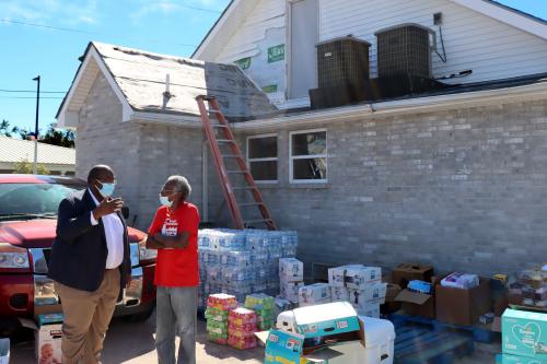 Marcus Coleman, director of faith-based initiatives with FEMA, talking with woman outside house with distribution supplies