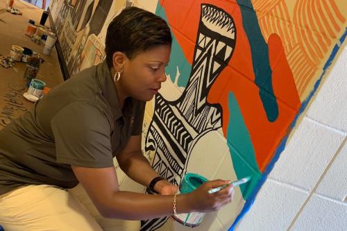 Nikki Clifton, president of Social Impact and UPS Foundation, painting mural on wall as a service project