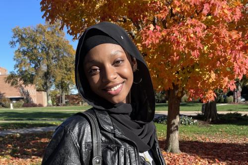 Sanaa Haamen, Howard student president of Muslim Student Association standing by fall colored tree