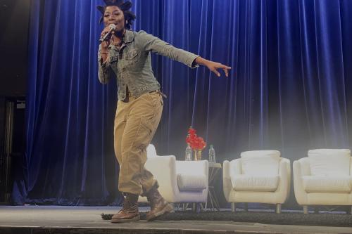 Black girl in cargo pants, jean jacket and boots sings on stage