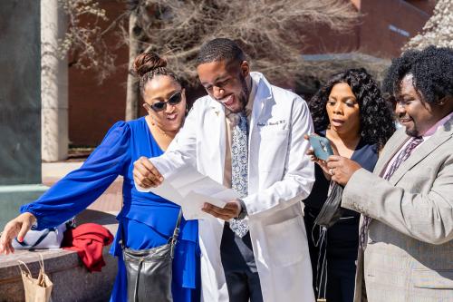 4th year medical student Joshua Metcalf opens his match-day letter with family following the long white coat ceremony. -Oscar Merrida