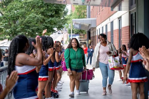 Student and her mother are welcomed by cheerleaders to the Howard University campus