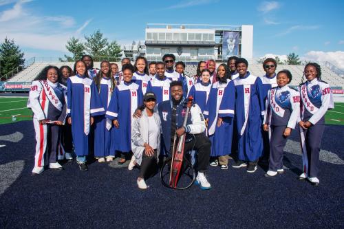 Showtime marching band poses with Professor Jami Ramberan and musician Kevin Olusola