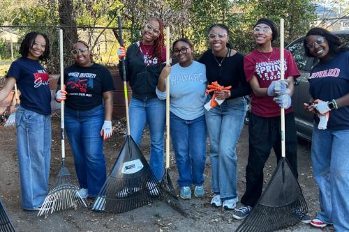 A group of seven howard students outside. Many of them are holding rakes. They are all wearing Howard-embossed sweatshirts and t-shirts. 