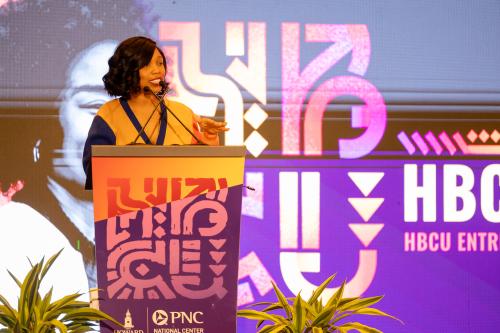 Black woman wearing orange stands at a podium at the PNC HBCU Empower conference