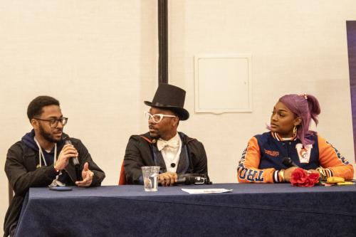 Alvin Hannon Blerdcon panelist. There are three people sitting behind a long table. Hannon is on the far left and he is holding a microphone