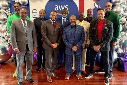 10 Black men in suits stand in front of Amazon Web Services and Howard University step and repeat