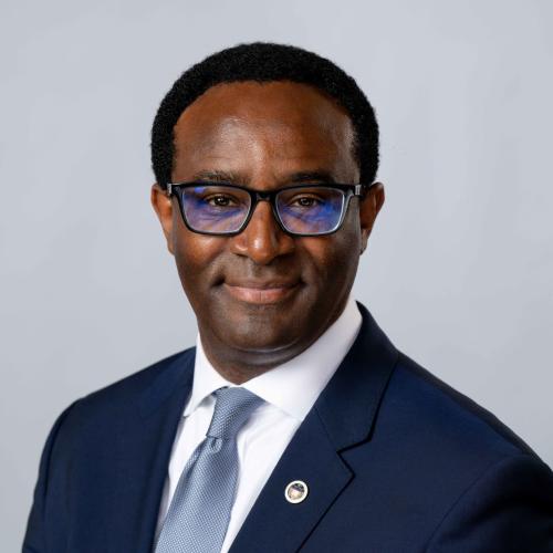 President Ben Vinson, III wearing a blue suit, white shirt, light blue tie and black glasses.