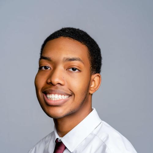 Davis Lucus smiling wearing a white button down shirt and red tie