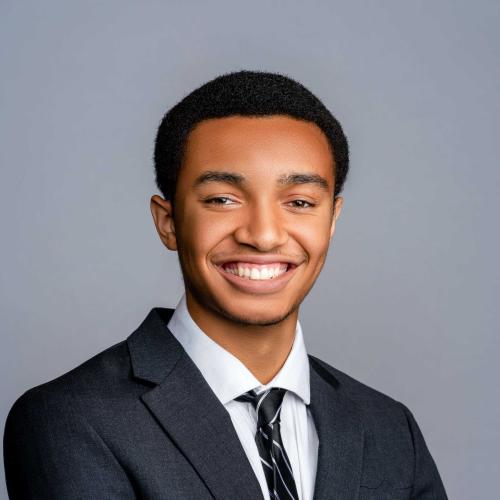 Cade Boggan wearing a dark grey suit with a white button down and black and white striped tie