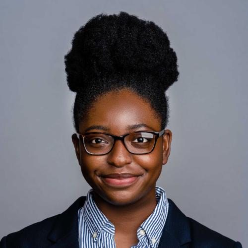 Sarah Bolarinwa wearing a navy blue blazer and a blue and white pinstripe button down shirt