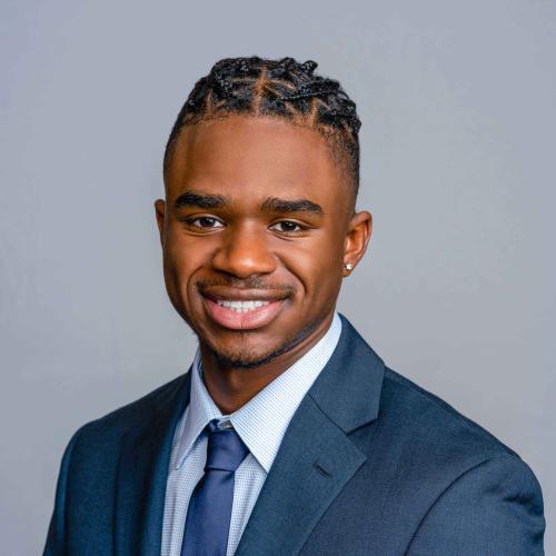 Miles Daniels wearing a blue suit jacket with a blue and white button down shirt and a blue tie