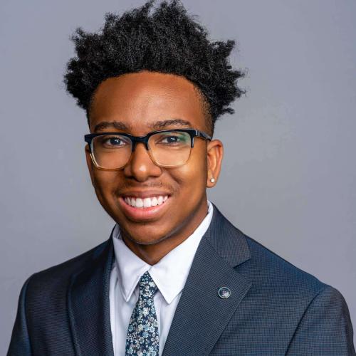 Brady Dye wearing a blue suit jacket with a white button down shirt and a flower patterned tie