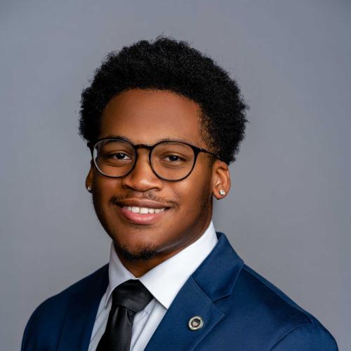 Gregory Hyson wearing a royal blue suit with a white button down shirt and a black tie