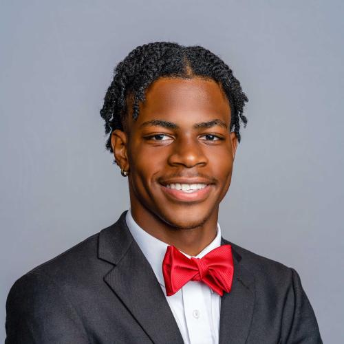 Isaiah Roberts wearing a black suit jacket with a white button down shirt and a red bow tie