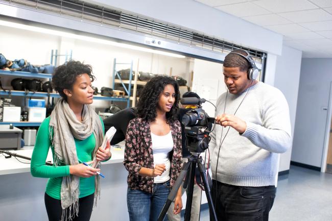 broadcast journalism students standing around a camera