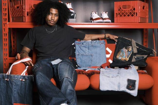Kenzell Munroe sitting in front of shelf with his designs