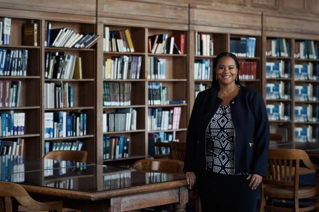 Danielle Holley stands among book cases in Founder's Library