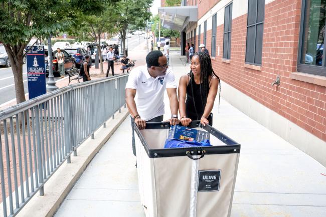 Dr. Ben Vinson III, the 18th upcoming president of Howard University, helps a student push a cart full of move-in items to College Hall South at Howard University 