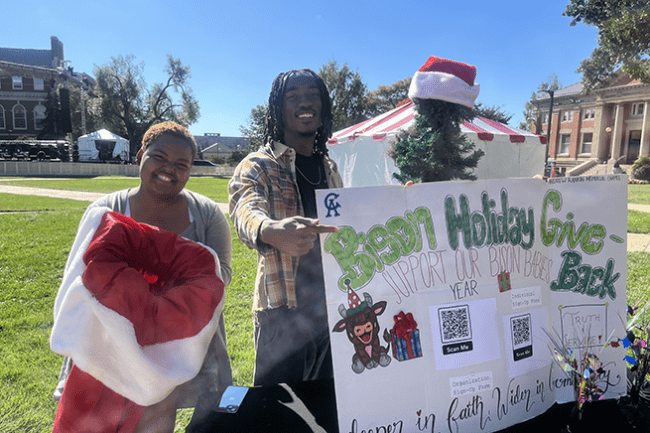 Two Howard Chapel Assistants on the yard with Bison Give Back sign