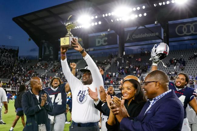 Howard University football coach Larry Scott holds up MEAC championship trophy