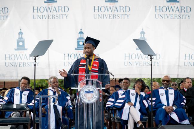 Joshua Taylor standing behind a podium giving a speech. He's standing on stage