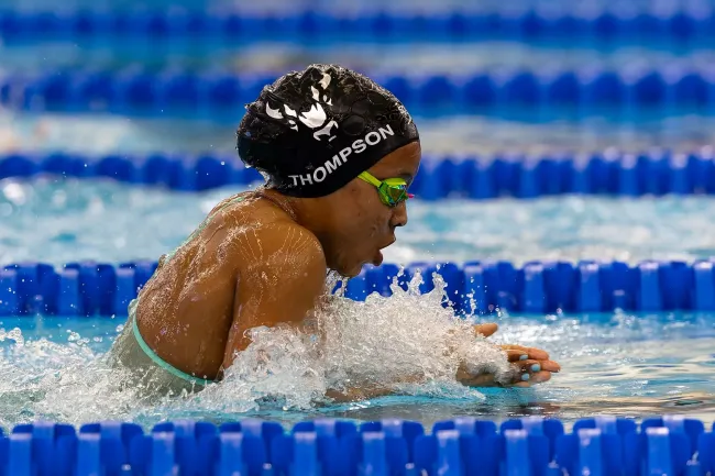 Black female swimmer with a Black swim cap comes up for air during a swim meet
