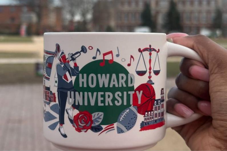 student holding starbucks and howard mug 