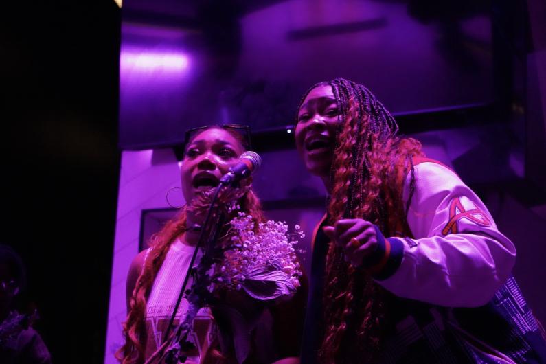 Two students on stage singing into a microphone