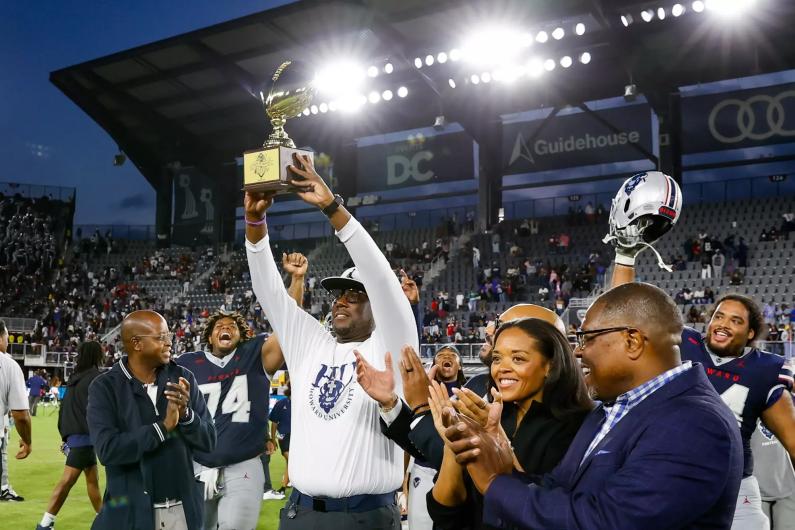 Howard University football coach Larry Scott holds up MEAC championship trophy