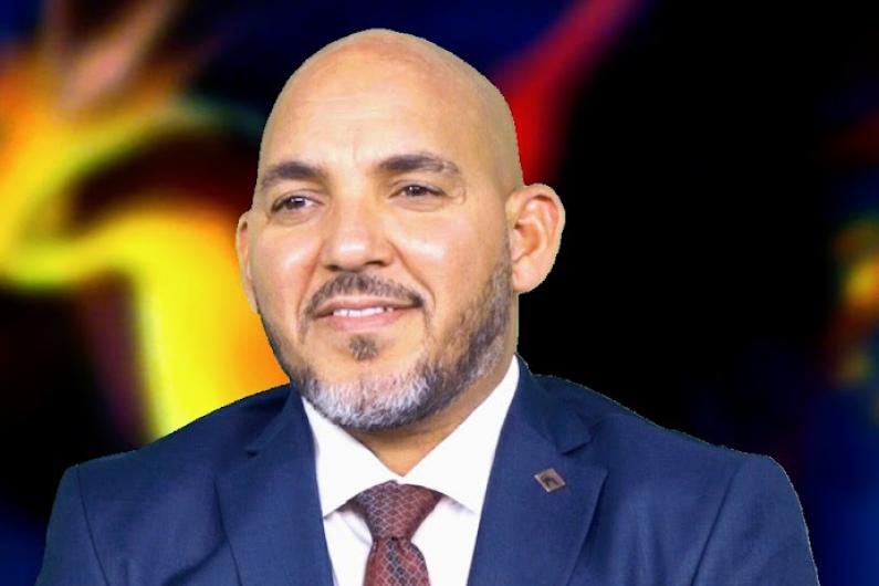 A man in a blue suit with a white tie and a tie on looking off to the left side of the picture