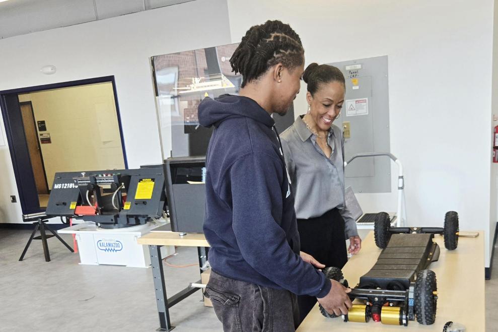 Dean Kimberly Jones standing at a table with a male student as they look at a 3D printed mechanical skateboard made in the Howard University Makerspace