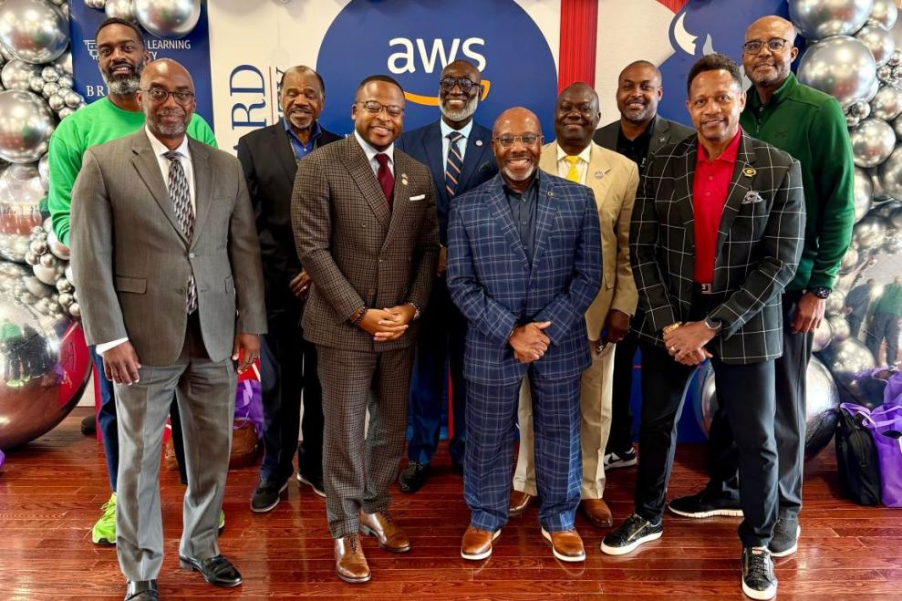 10 Black men in suits stand in front of Amazon Web Services and Howard University step and repeat