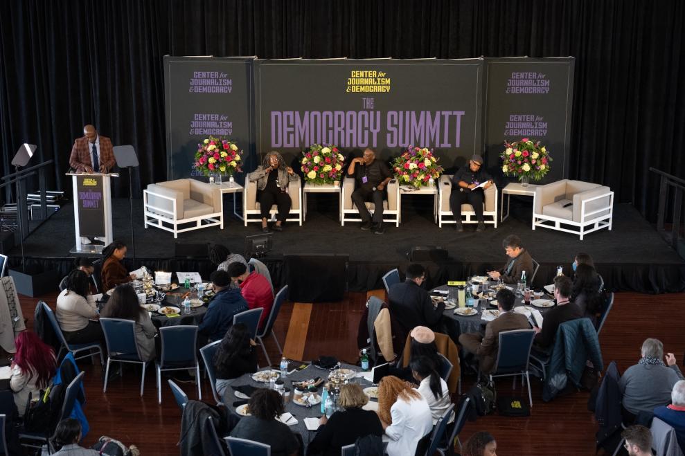 Three professionals sit on stage in front of a crowd at the Center for Journalism and Democracy Summit in 2024