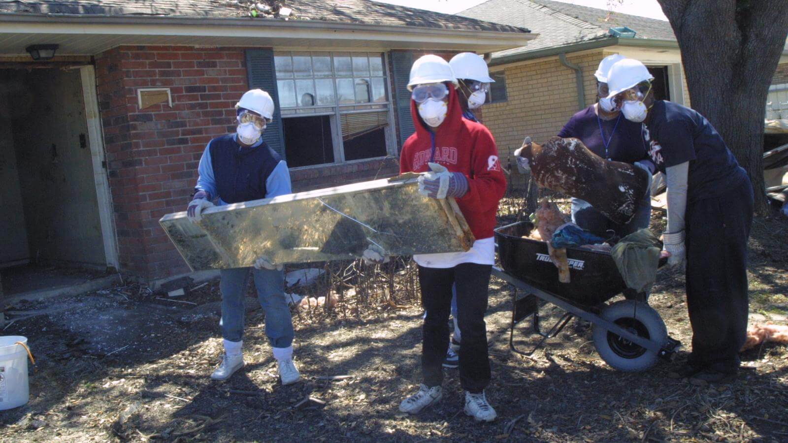Howard university students amid damage to a home after hurricane katrina. they are clearing debris from the destroyed homes.