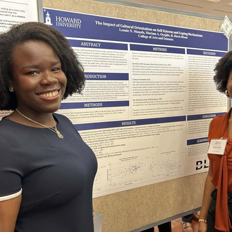 Two female college students standing in front of a poster board with research findings