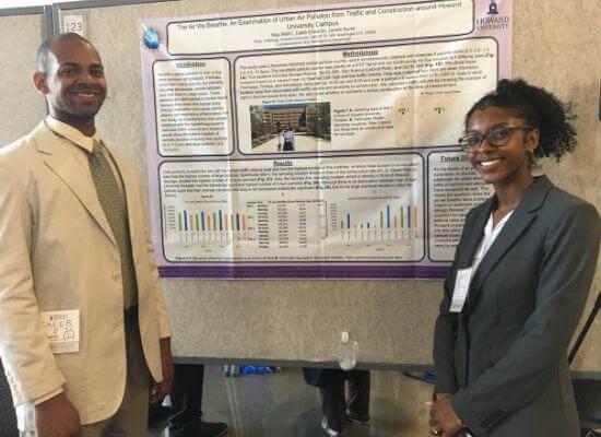Female and male standing by environmental science poster