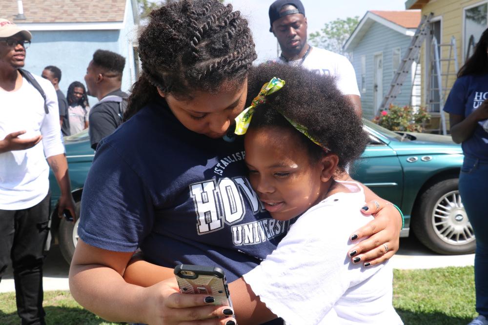 Child hugs student volunteer outside