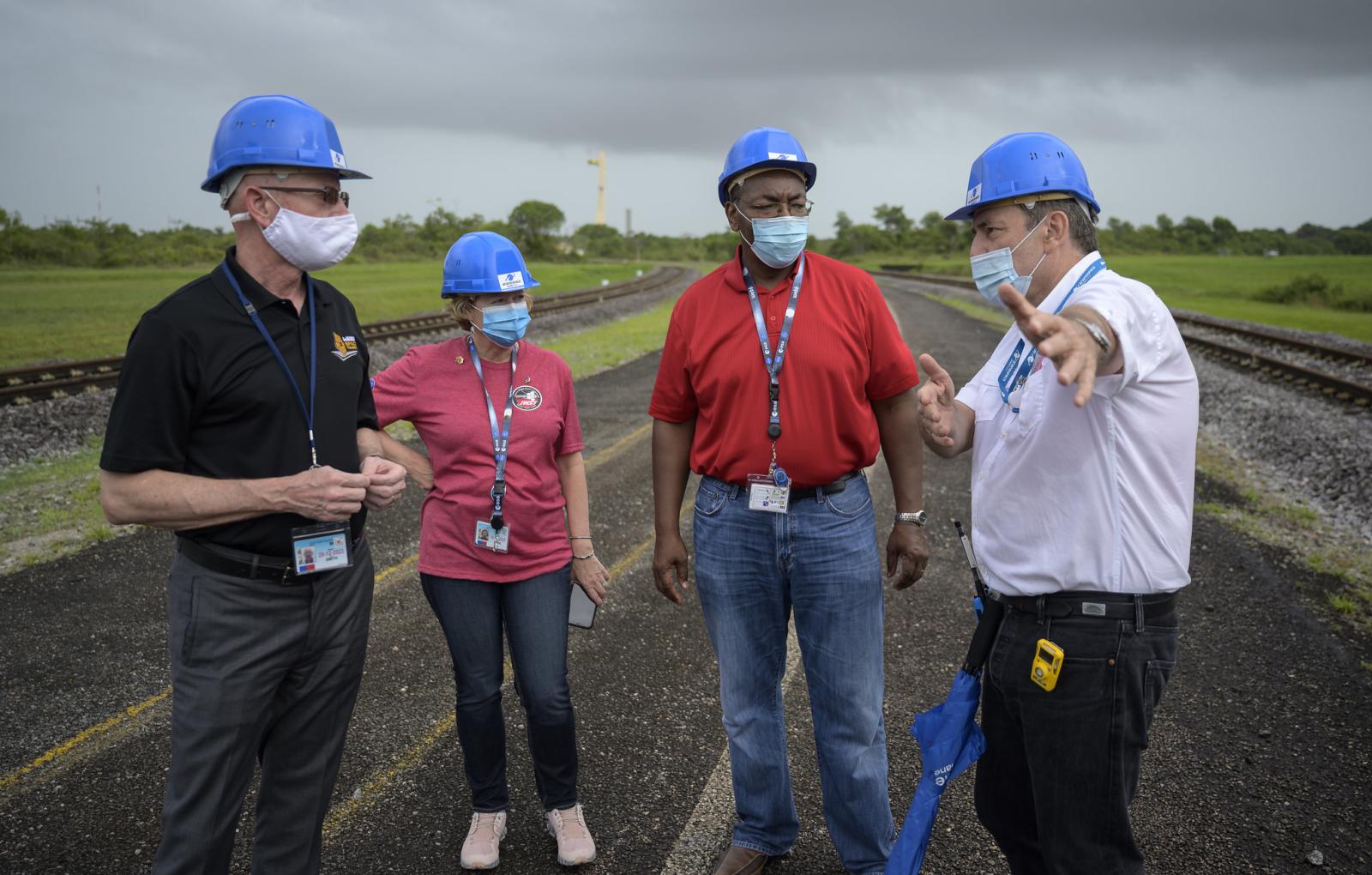 NASA scientists with hard hats standing by launchpad for Webb telescope