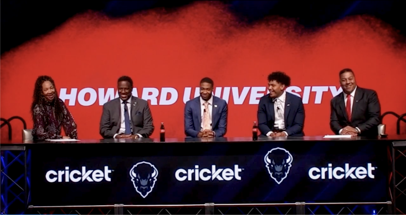 Walker in a sports panel of five people with red background that says Howard University