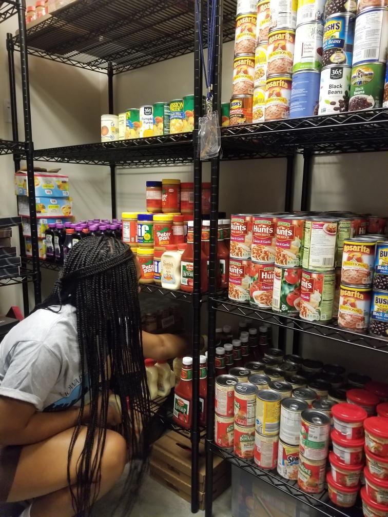 student restocking shelf of canned goods