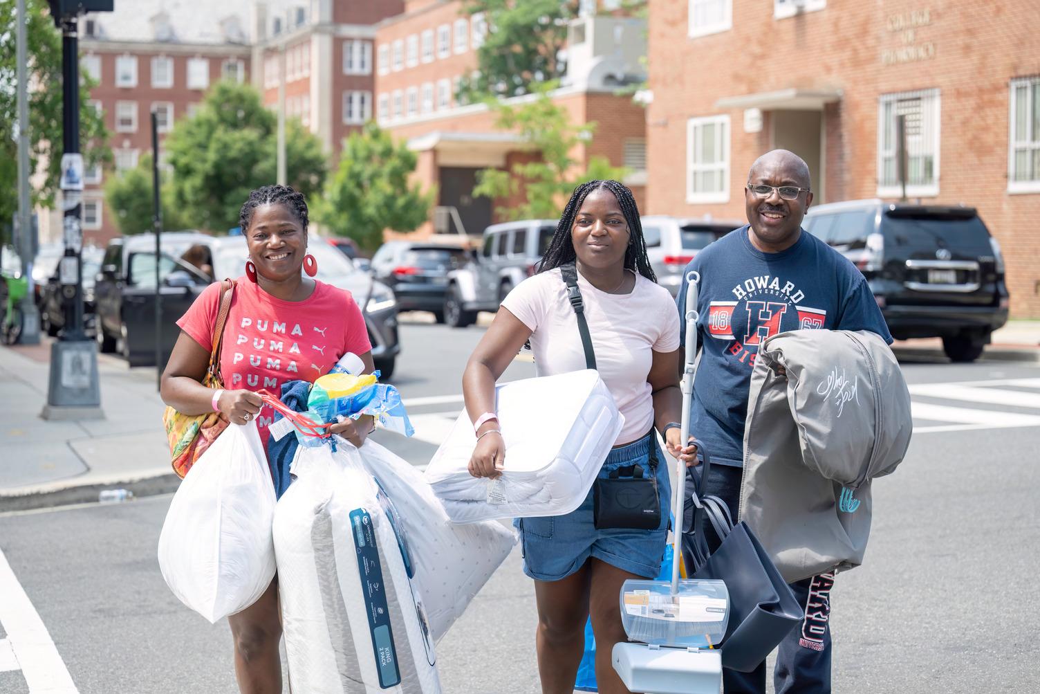 Provost Anthony K. Wutoh helps a mother and daughter as they move in the Saturday before classes begin. (Photographer: Justin D. Knight) 