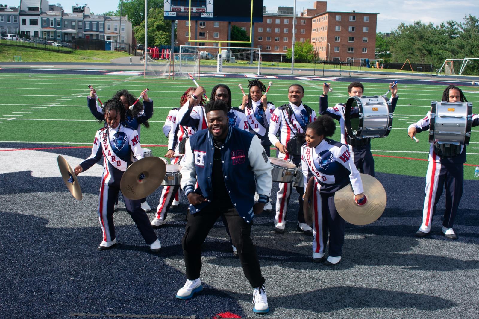 Kevin Olusola dances on football field with members of the HU Showtime Band