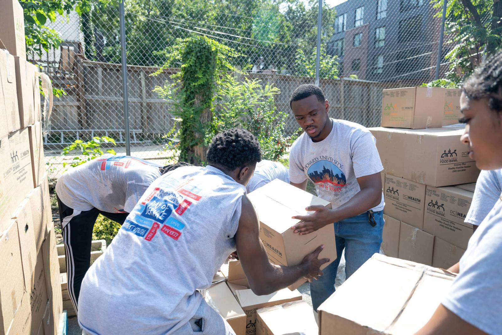 College students unpacking and opeing cardboard boxes while outside. 