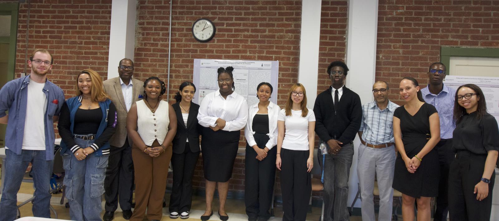 A group of 10 people smiling at the camera. They are standing in a classroom at a university, standing in front of a poster with research findings.