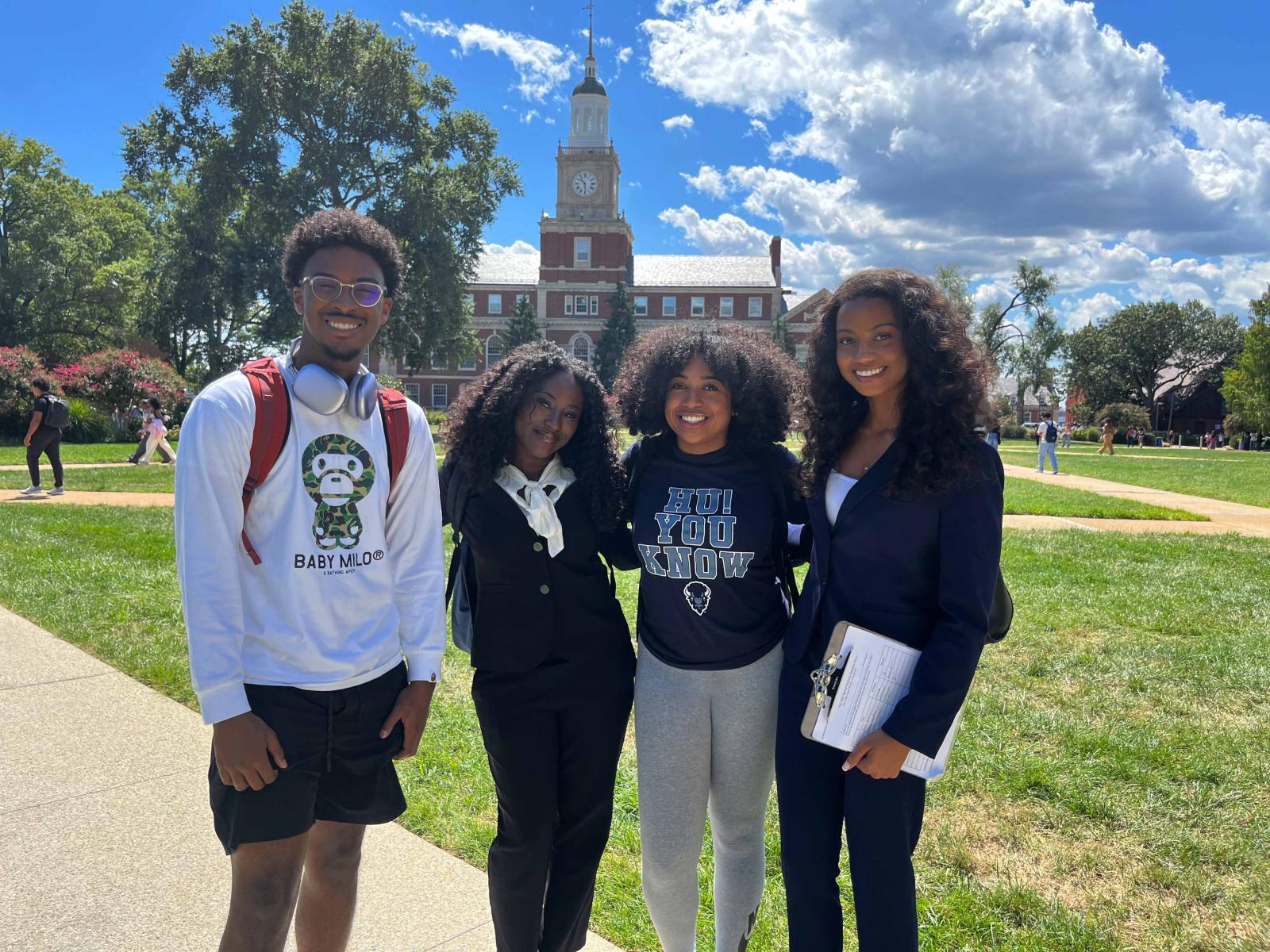 Four Howard University students pose for a photo on The Yard in front of Founder's Library